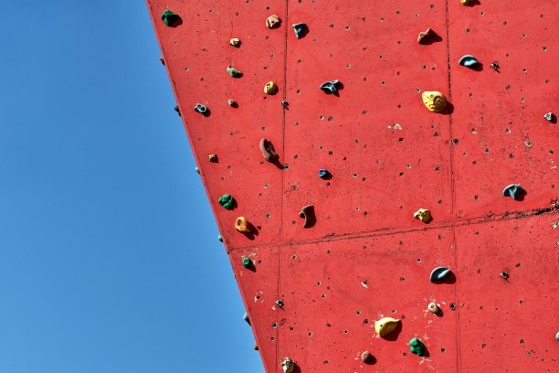 红色的人工攀岩墙前，蓝天无云图片下载