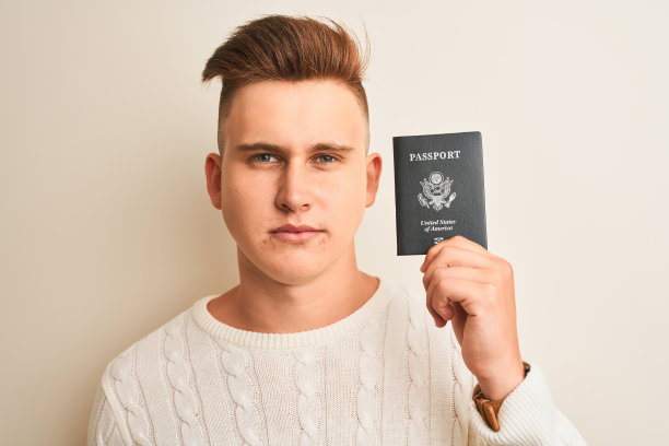 年轻英俊的男子拿着美国护照过孤立的白色背景，自信的表情上聪明的脸认真思考图片下载