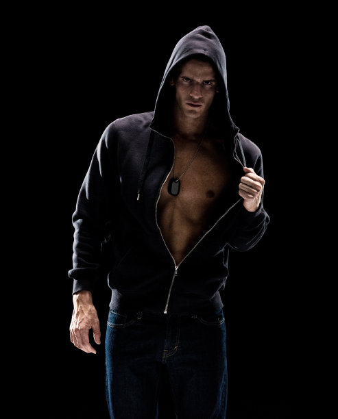 一名男子仅/腰部以上/四分之三长度的20-29岁的成年人英俊的白人男性/年轻男子前面的黑色背景穿着牛仔裤/连帽夹克/衬衫/汗衫/凉爽的态度/黑色的颜色/性感图片下载