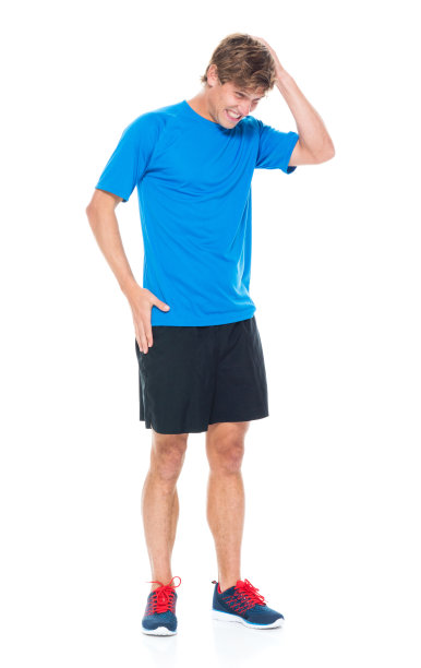 全身长度20-29岁英俊的人白人男性/年轻男子运动员/运动员站在白色背景下穿着运动服/跑步短裤/短裤/ t恤/衬衫/手在头发图片下载