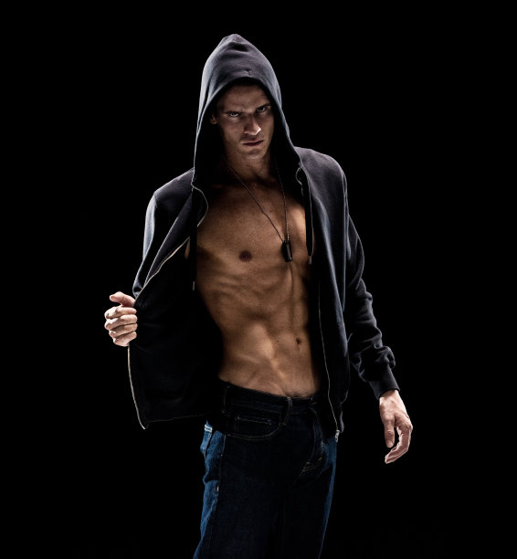 一个男人只/腰部以上/四分之三长度的20-29岁的成年英俊的白人男性/年轻男子脱衣舞娘在黑色背景穿着牛仔裤/连帽夹克/衬衫/汗衫/完全解开/凉爽的态度图片下载