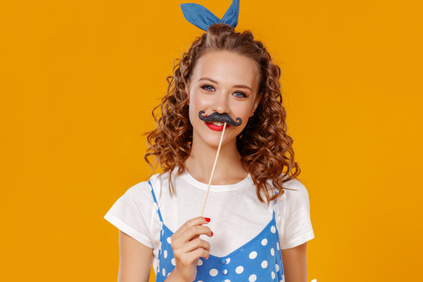 年轻美丽有趣的女孩与胡子在黄色的背景图片下载