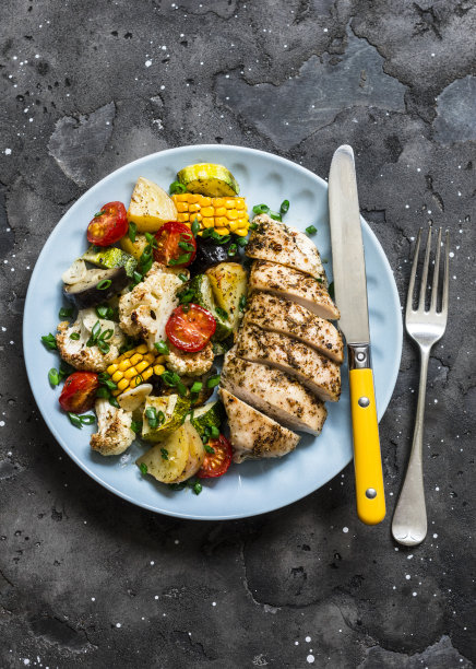鸡胸肉与土豆，花椰菜，玉米，茄子，西葫芦，樱桃番茄在一个黑暗的背景，俯视图。健康饮食概念图片下载