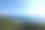 晴朗的蓝天和海平线。新鲜的绿色草地和树木前景。图片下载