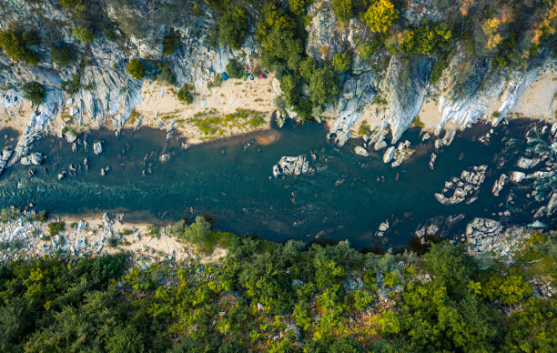 航空照片的河流流过一个山谷与绿色的森林和岩石在河里图片下载