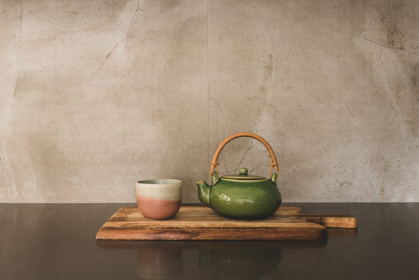 木制的陶瓷杯和绿色茶壶，灰色的背景图片下载
