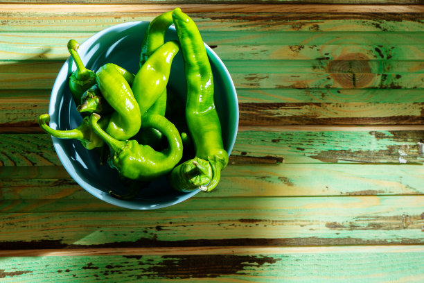 蓝色的碗里放着辛辣的青椒，背景是木质的，有阴影。副本的空间。顶视图的食物。不含硝酸盐、转基因的生态蔬菜。天然新鲜农产品。食物的照片背景图片下载