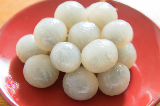 剥去龙眼，置于红瓷盘上孤立图片下载