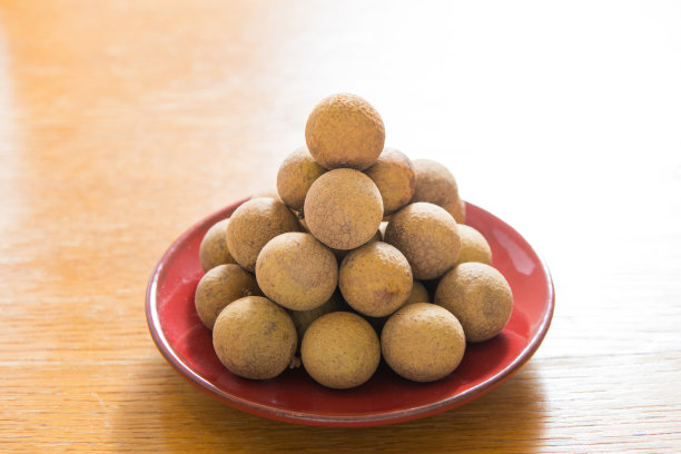 新鲜龙眼放在红瓷盘上孤立图片下载