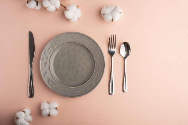 在精致的餐桌上，用棉花树枝将灰色的盘子和刀叉清空，为你的菜单或食谱留出空间。菜单卡餐厅和餐桌设置。水平的照片。平躺图片下载