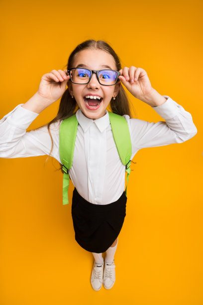 兴奋的小学生戴着眼镜在黄色背景上摆姿势图片下载