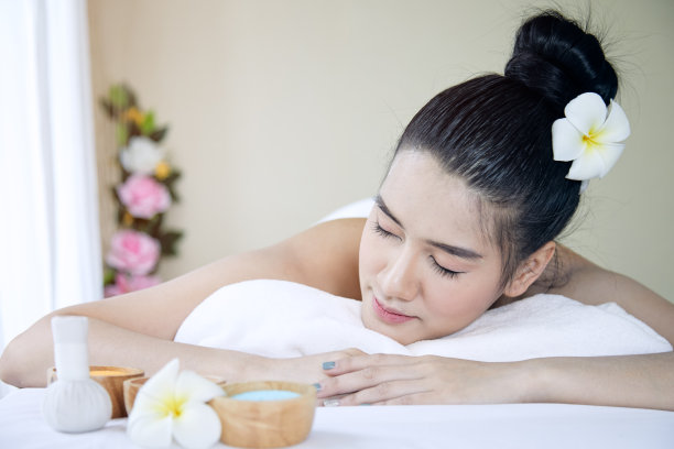 近距离的迷人的年轻亚洲女人躺着和闭上眼睛，在白色的床上接受水疗治疗图片下载