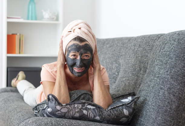 老妇人带着面膜躺在家里的沙发上图片下载