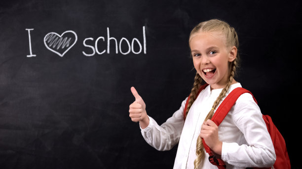 我爱学校的黑板上，笑着竖起大拇指的女孩的手势，教育图片下载
