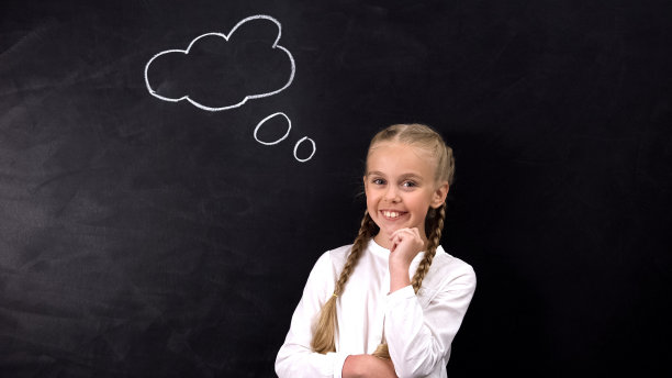 微笑的小学生看着相机，想法在黑板上签名，创意概念图片下载