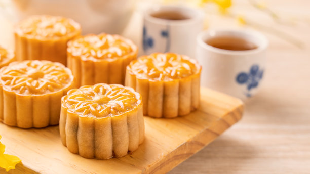 中秋节日月饼概念设计，月饼，茶具放在明亮的木桌和餐盘上。图片下载