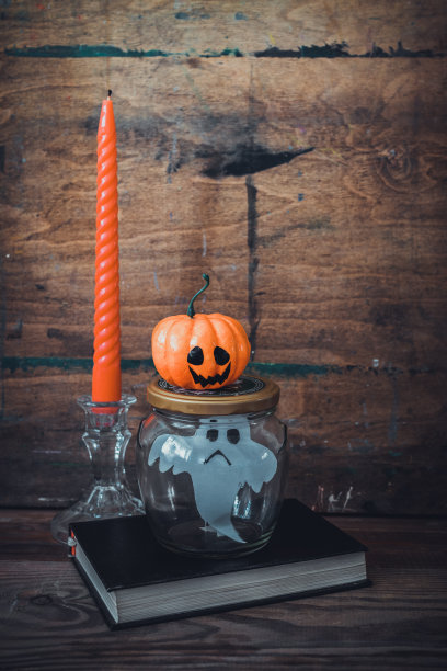 玻璃罐里的纸鬼和蜡烛旁的滑稽南瓜。是时候庆祝万圣节了。图片下载