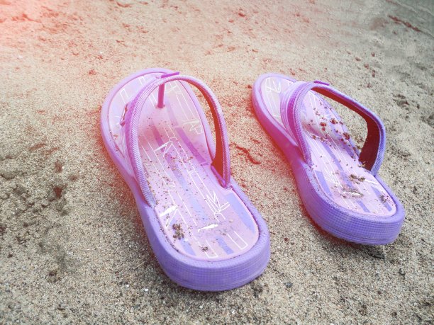 沙滩上的紫色拖鞋。近距离图片下载