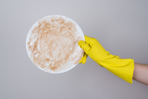 洗脏盘子的概念。侧面侧面裁剪近距离照片的手在明亮的保护橡胶手套拿着极其肮脏的陶器孤立的灰色背景图片下载