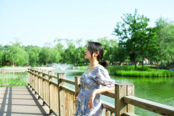 年轻美丽的女子站在桥上，公园背景，河边图片下载