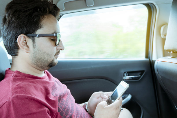年轻的商人在车里使用智能手机图片下载