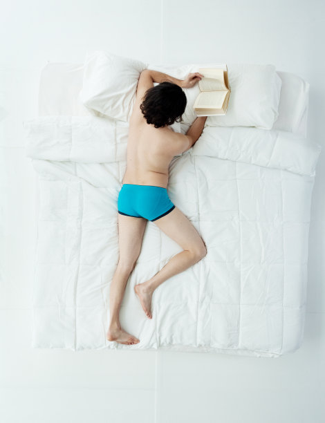 全身/一人/正上方的20-29岁的成年英俊的人/长发白人男性学生/大学生躺下/放松/休息/睡觉/醒来在卧室的白色背景图片下载