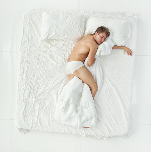 全身/一人/直接上方视图/侧视图/ 20-29岁的成年人英俊的人/苗条的棕色头发/短发白人男性/年轻男子在白色背景的卧室/凉爽的态度谁是赤脚图片下载