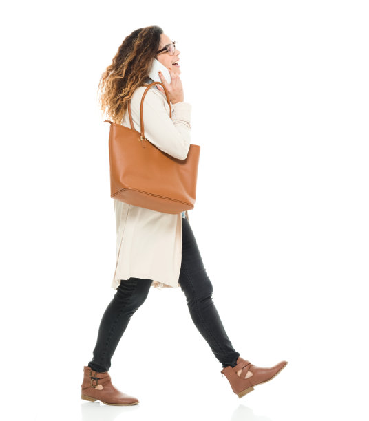 全长/侧视图/ 30-39岁的成年人美丽的卷发/长头发波多黎各种族/拉丁美洲和西班牙裔的女性/年轻女性在白人背景前/冷静的态度和使用智能手机图片下载