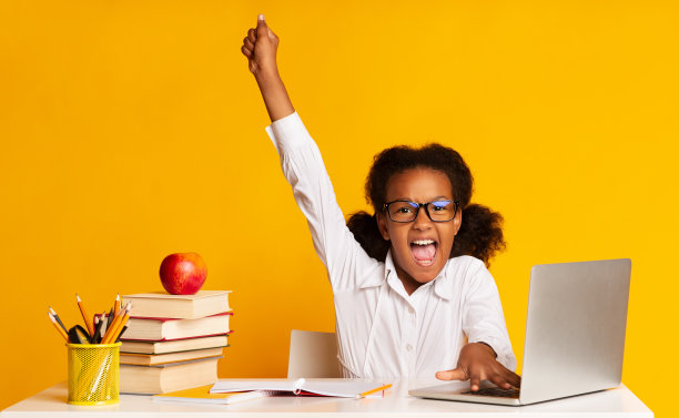 非洲裔女学生在工作室里举手，坐在笔记本电脑前图片下载