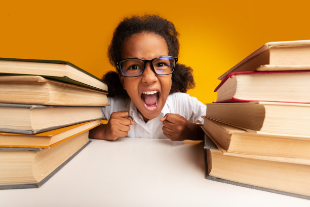 在演播室里，一个小学生坐在书堆中间大喊大叫图片下载