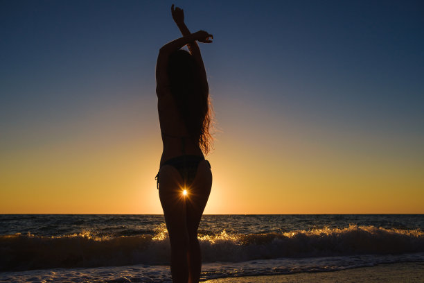 年轻苗条美丽的女人在日落海滩，顽皮，跳舞，跑步，波西米亚服装，独立风格，暑假，阳光，有乐趣，积极的心情，浪漫，泼水，剪影，快乐，照片色调图片下载