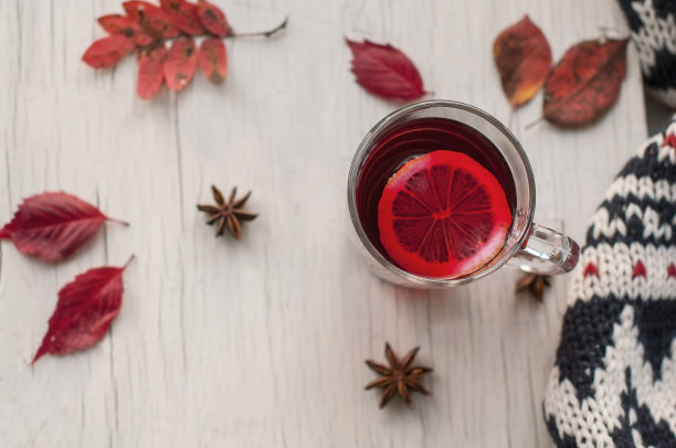 秋天舒适和温暖的静物从一杯红茶与柠檬，干燥的秋天红叶，豆蔻和蔓越莓浆果在一个白色破旧的复古背景"n图片下载