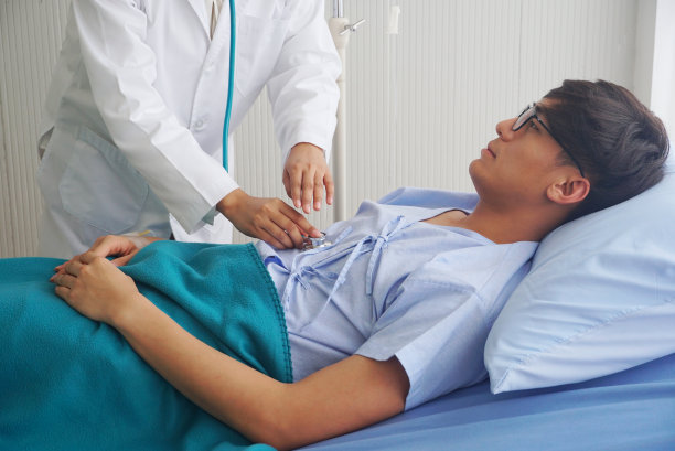 医生正在为躺在床上的亚洲男性病人测量脉搏。图片下载