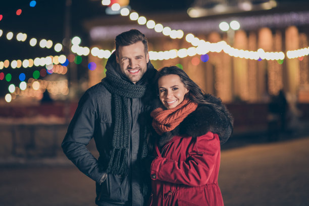 这是一对情侣在新年午夜参加城市公园的照片，天气寒冷，他们穿着温暖的冬季夹克站在户外图片下载