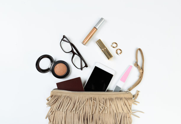 时尚概念:平铺的棕色皮质女包打开，太阳镜和智能手机在白色背景。图片下载