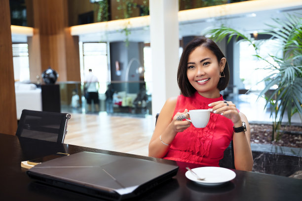 亚洲女商人喝咖啡，在办公室工作图片下载