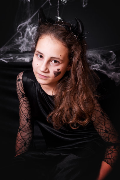 小女孩穿着万圣节服装，背景是黑色。图片下载