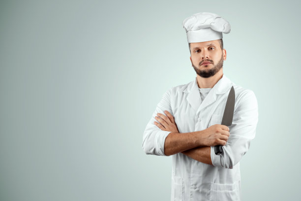 一个留着胡子的男人，一个戴着帽子的厨师，手里拿着一把刀孤立在白色的背景上。烹饪,食谱,烹饪。图片下载