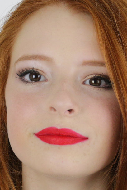 这张特写照片是一个14 / 15岁的红发少女，皮肤苍白，脸上有雀斑，坐在卧室里测试她嘴唇上亮红色的口红，嘴唇噘起自然的脸部妆容图片下载