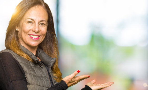 美丽的中年女子穿着冬季背心，张开手自然地微笑着走进图片下载