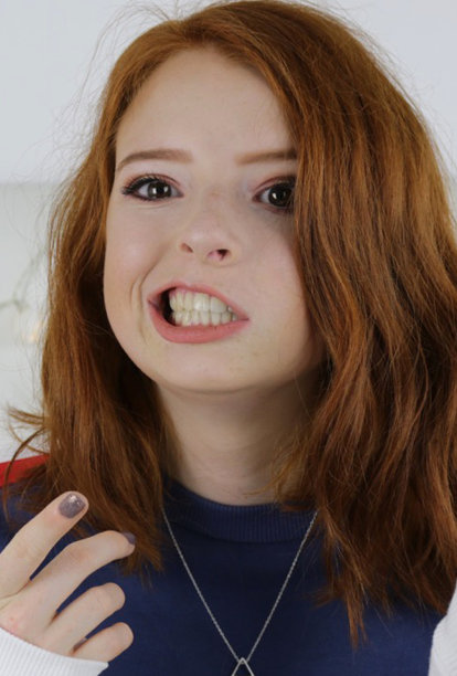 照片中的14 / 15岁红头发、皮肤苍白、长着雀斑的少女坐在卧室里看着镜头，神情轻松，微笑着做鬼脸图片下载