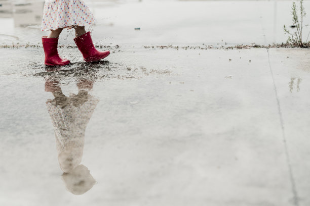 小女孩在水坑里玩，开心极了。库存图片图片下载