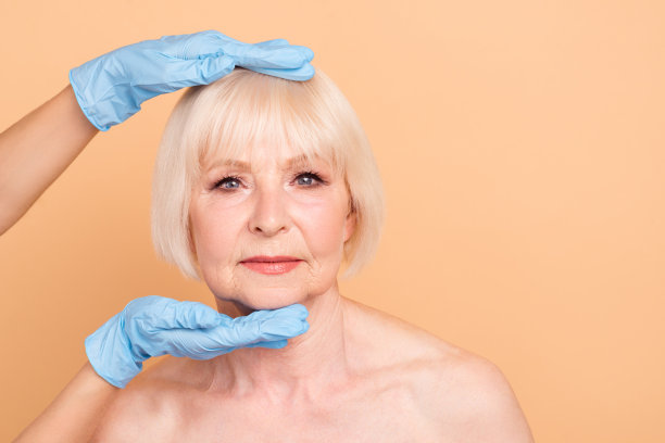 近距离照片美丽，她，她，年老的女士，完美的过程，外科医生，触摸，手，手臂，观察面部皮肤，透明质酸美容注射后，裸孤立的粉彩米色背景图片下载