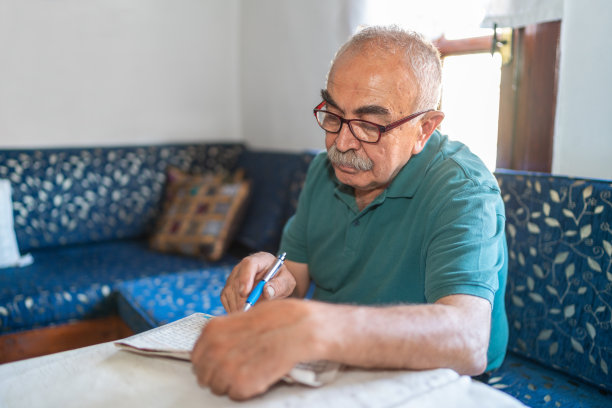 一个老人坐在扶手椅上做填字游戏图片下载