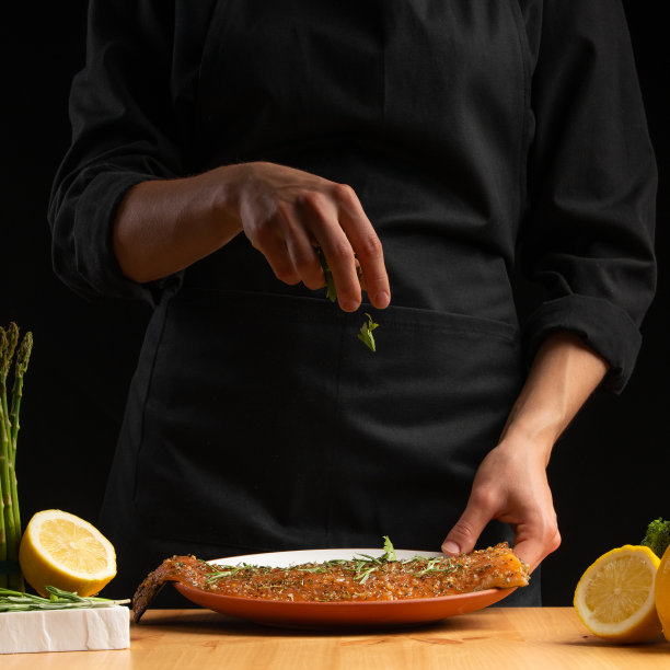 厨师烹饪海鲜时，在红色的鱼上撒上迷迭香、鲑鱼或鳟鱼。运动，餐厅菜单，食谱书，亚洲菜，自制食谱。广场的照片图片下载