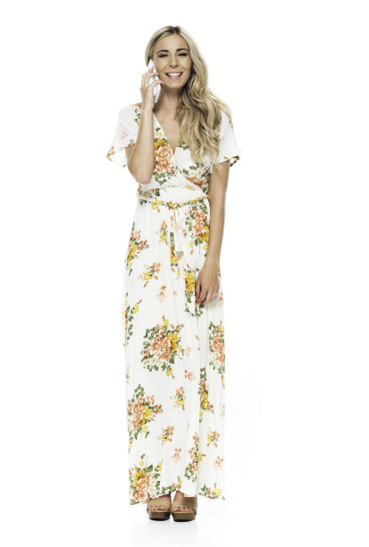 正面图片/全身长度20-29岁的成年金发/长发白人年轻女性站在白色背景下，穿着连衣裙/长裙，正在交谈/微笑/快乐/愉快地拿着手机/使用智能手机图片下载