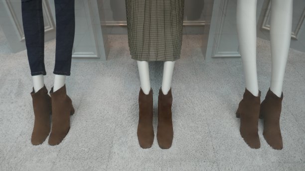 修长的腿树女性人体模型在牛仔裤，裙子和棕色皮革踝靴。关闭图片下载