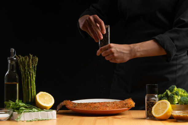 厨师烹饪海鲜，红色鱼撒胡椒，鲑鱼或鳟鱼在黑色的背景。运动，餐厅菜单，食谱书，亚洲菜，自制食谱。广场的照片图片下载