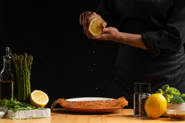 厨师烹饪海鲜，红色的鱼倒柠檬，鲑鱼或鳟鱼在黑色的背景。运动，餐厅菜单，食谱书，亚洲菜，自制食谱。广场的照片图片下载