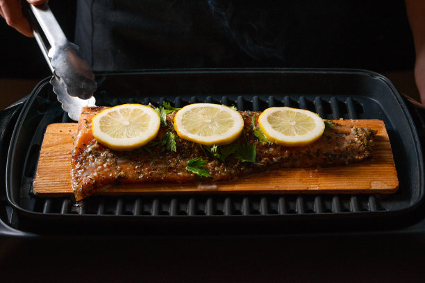 厨师烹饪，海鲜，红色烤鱼与烟，鲑鱼或鳟鱼在黑色的背景。运动，餐厅菜单，食谱书，亚洲菜，自制食谱。水平照片，特写图片下载